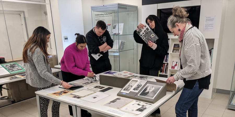 Colour photograph of staff viewing a display of archival material from photography galleries on a table