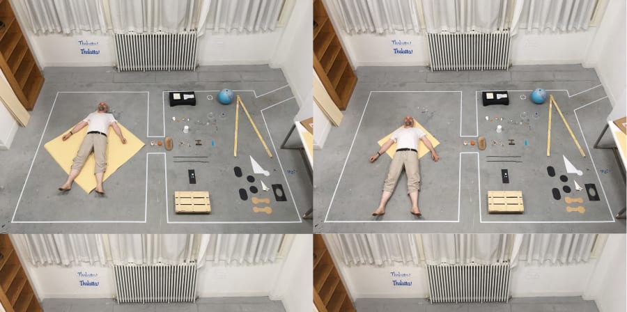 man laying down on studio floor aerial image with work around him