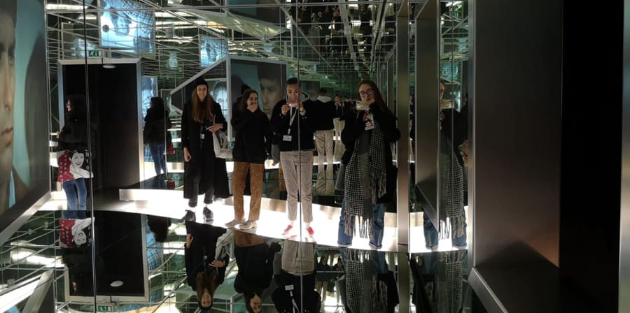 Students are reflected on the walls and ceilings of a mirrored exhibition space at the Berlinale.