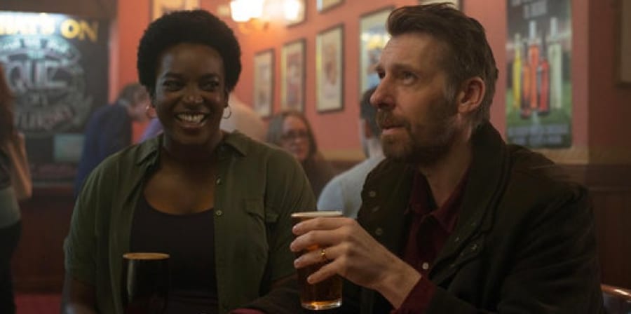 Still from the film Killed by my Debt, featuring characters drinking at a pub