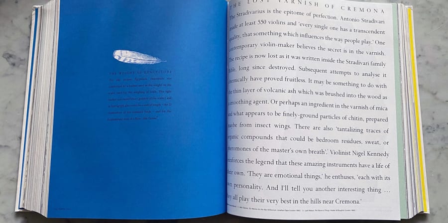 A book opens to a blue and white page exploring the design history of violins.