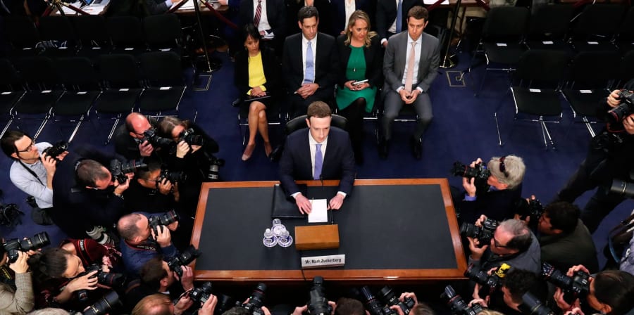 Mark Zuckerberg, CEO of Facebook, sits at a table testifying before Congress.