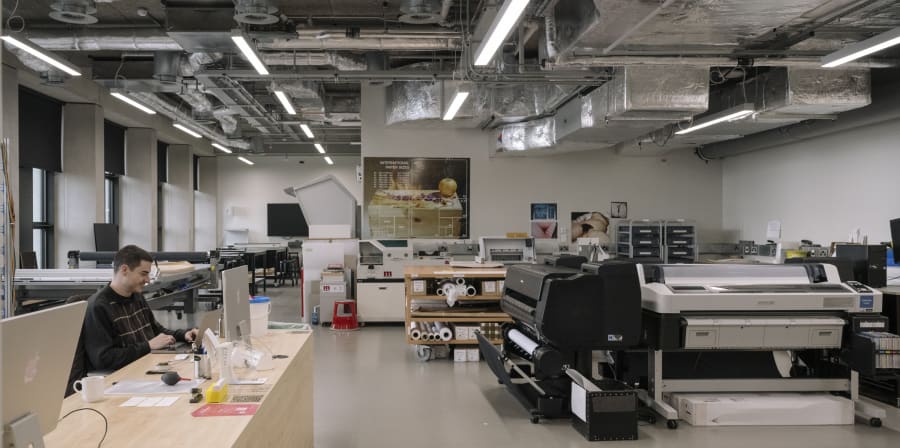 Person sitting at a desk in a large room with equipment such as charts and scanners.