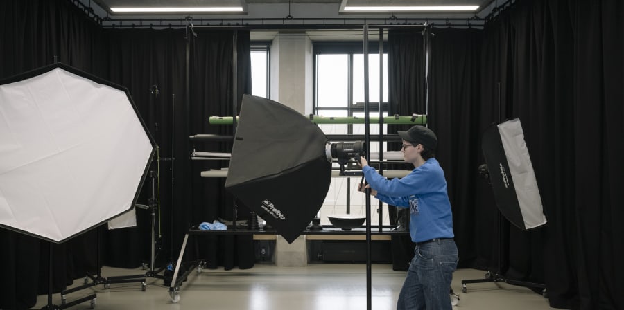 Person pointing a camera in a dark room with black curtains.