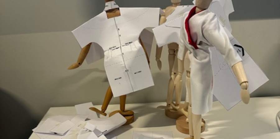 Miniature mannequins in paper dresses.