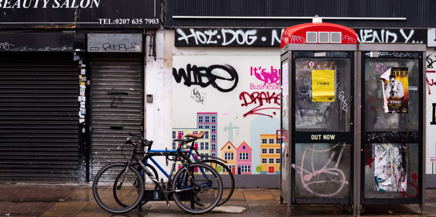 Photo of stabbing location, with a bicycle, graffiti, and phone boxes.