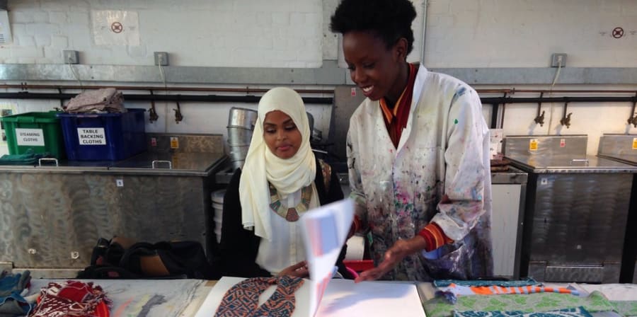 Print technician standing working with a student in the fabric workshop