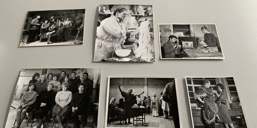 Colour photograph of a selection of black and white photographic prints showing tutors and students at work in sculpture studios, theatre productions and in group photo settings. 
