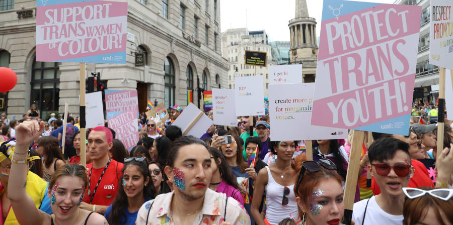 People marching in Pride, holding placards that say 'Protect Trans Youth'