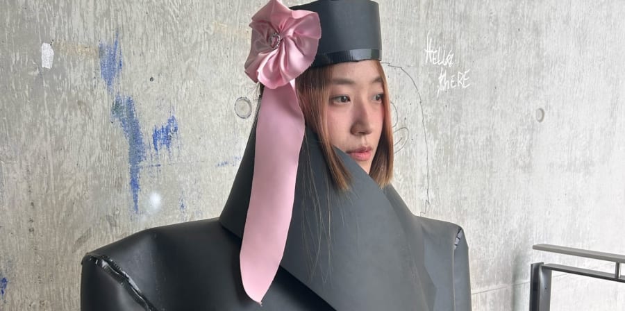 A model in an editorial shoot wearing an oversized tailored jacket and matching hat