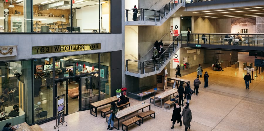 An angle shot of the Street at CSM showing part of the Street just inside the barriers and some of the upper levels and signage over the canteen. Students are visible throughout the spaces.