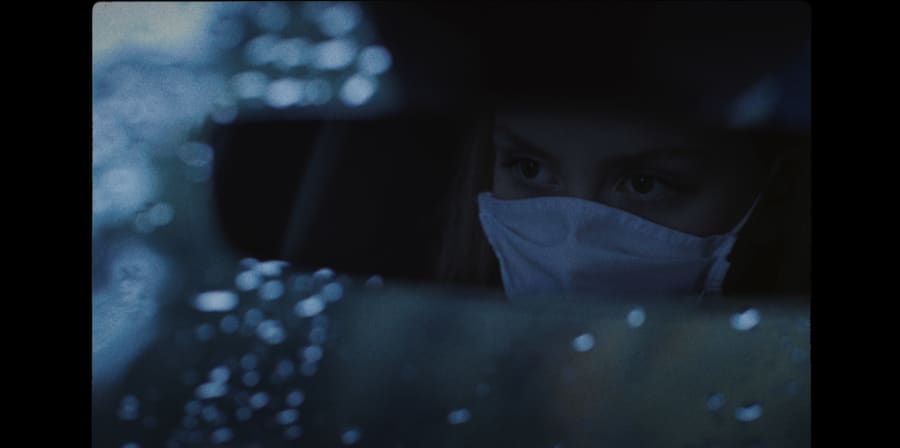 A girl wears a face-mask in a car.