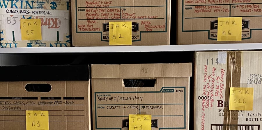 Photograph showing archive boxes on shelves marked with post-its with the initials 'J.A.K.' for Jo Ann Kaplan, and numbers