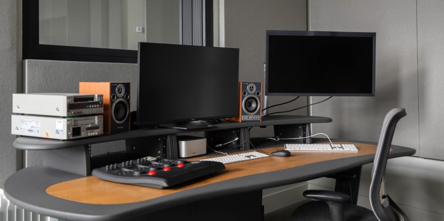 Desk with screens, speakers, editing equipment.
