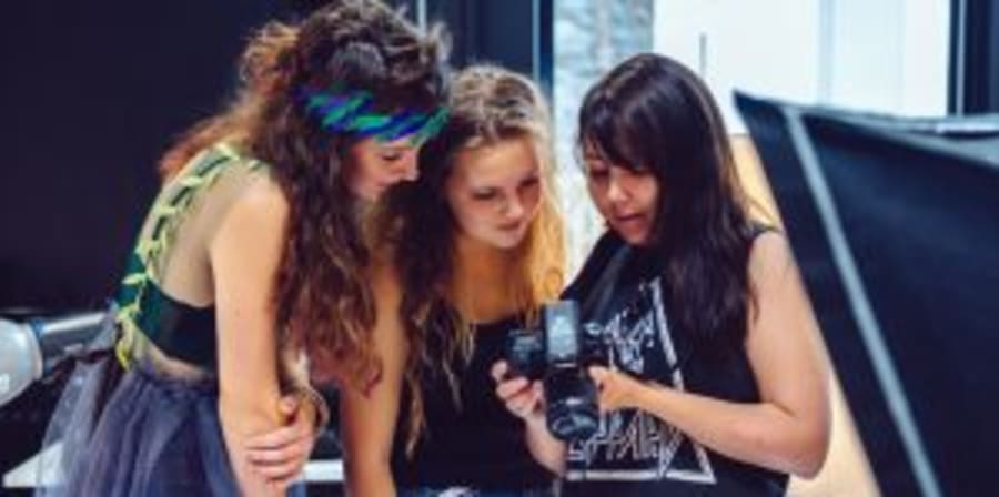 Students gathering around a camera on a photoshoot