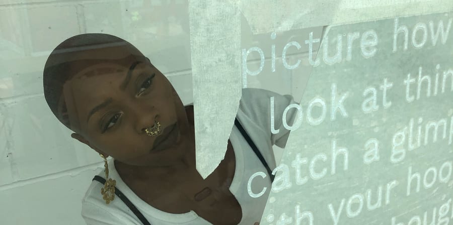 photo of Rayvenn Shaleigha D’Clark installing in the window of gallery