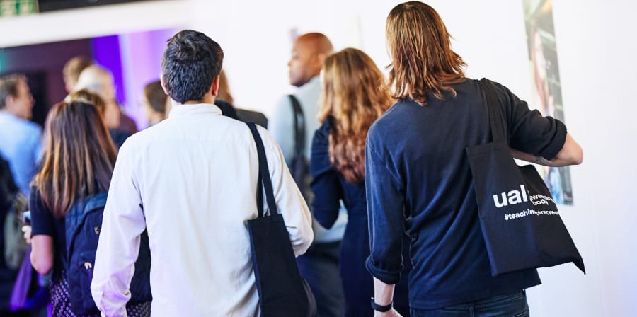 People holding tote bags walking along a corridor