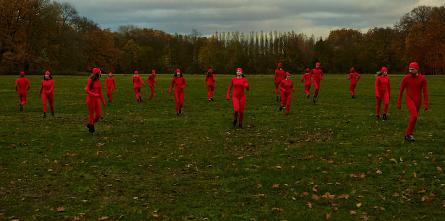 An image of multiple people wearing all read in a green field of grass