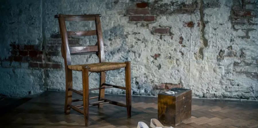 Wooden upright chair with a pair of white shoes and wooden box on floor