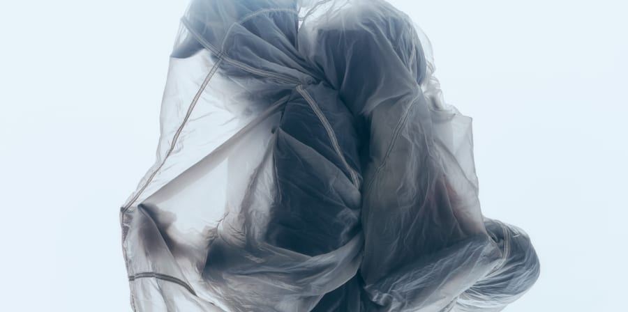 Hiker with cap and backpack and full clear covering over him.