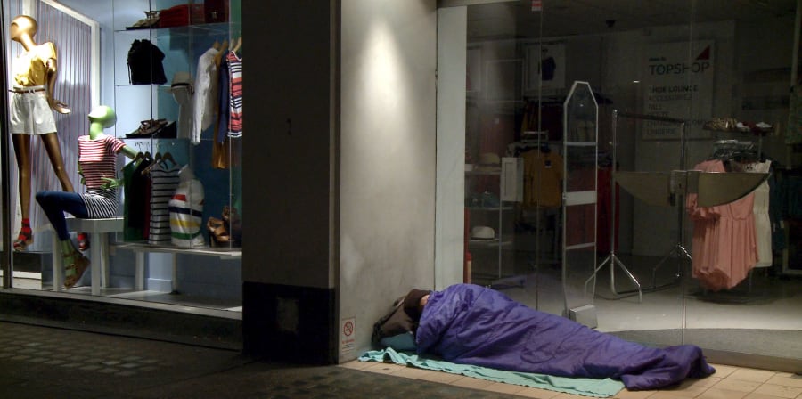 Movie still of a homeless person sleeping in a shop corner