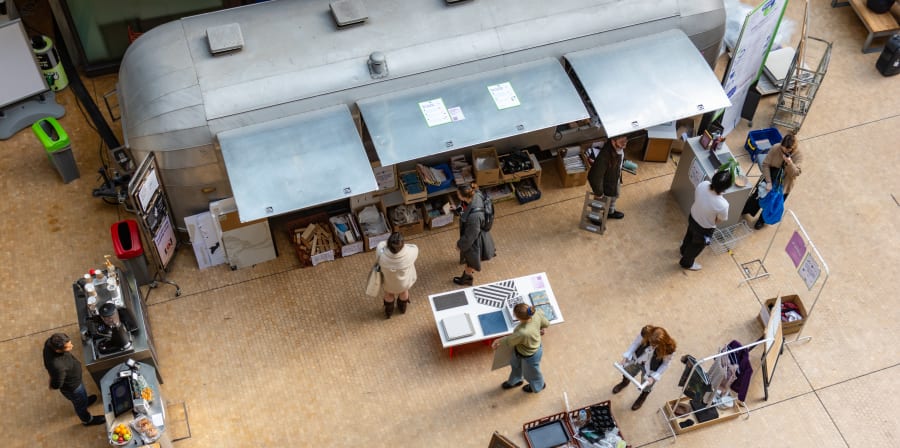 Arial shot of an airstream van at Central Saint Martins with open awnings and people outside it. 