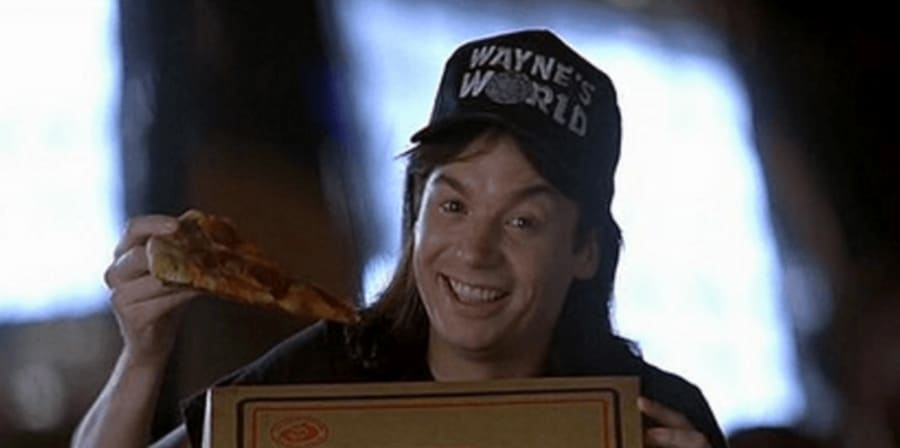 Still from the film Wayne's World, showing Wayne posing with a pizza from Pizza Hut.