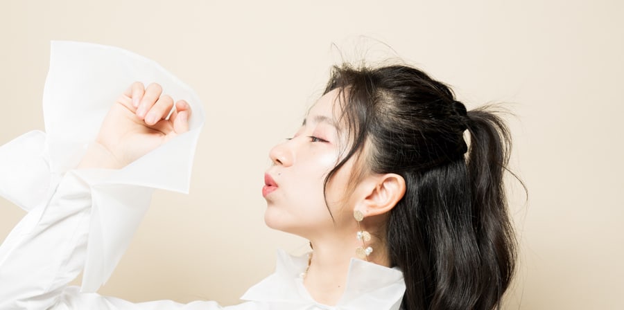 Woman in a structured white shirt with flared sleeves posing against a beige background.