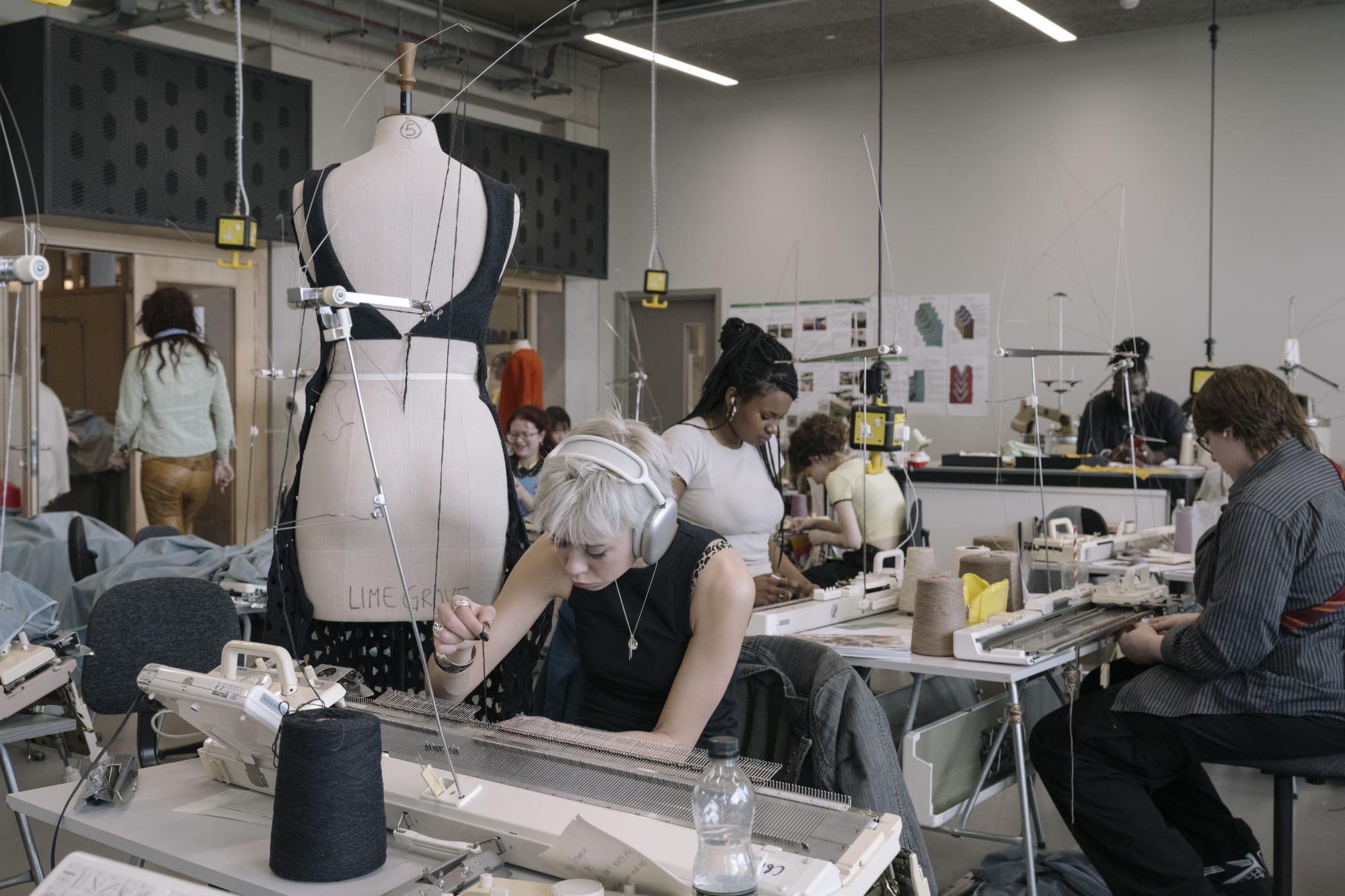 People using sewing machines, with a mannequin in the middle of the room.