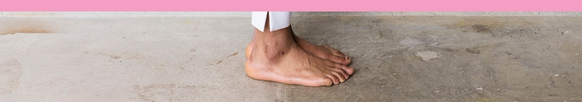 A foot stood on a concrete floor, a light pink strip covers the top of the phot