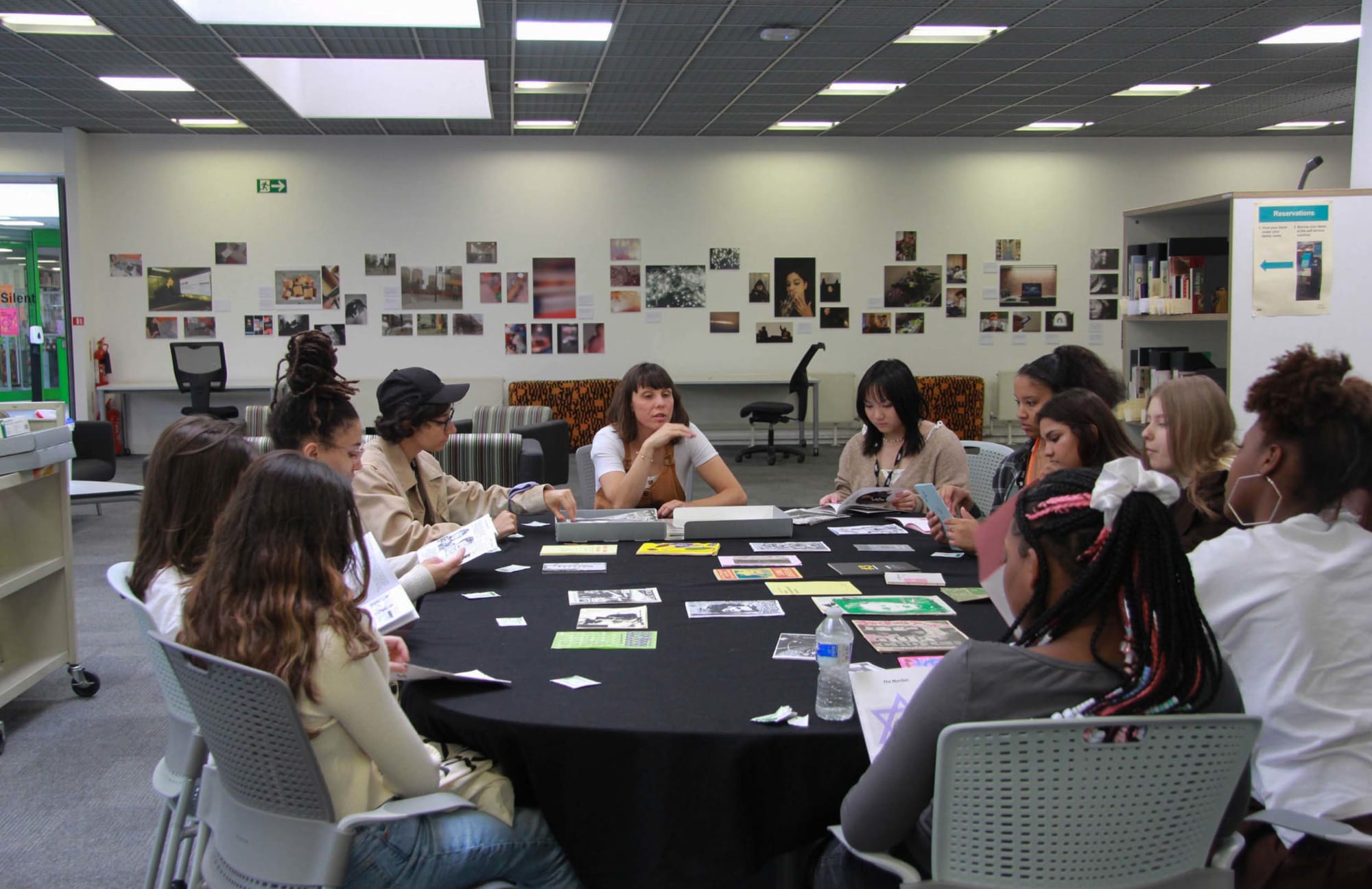 Students and a tutor sitting around a table with multiple images on it