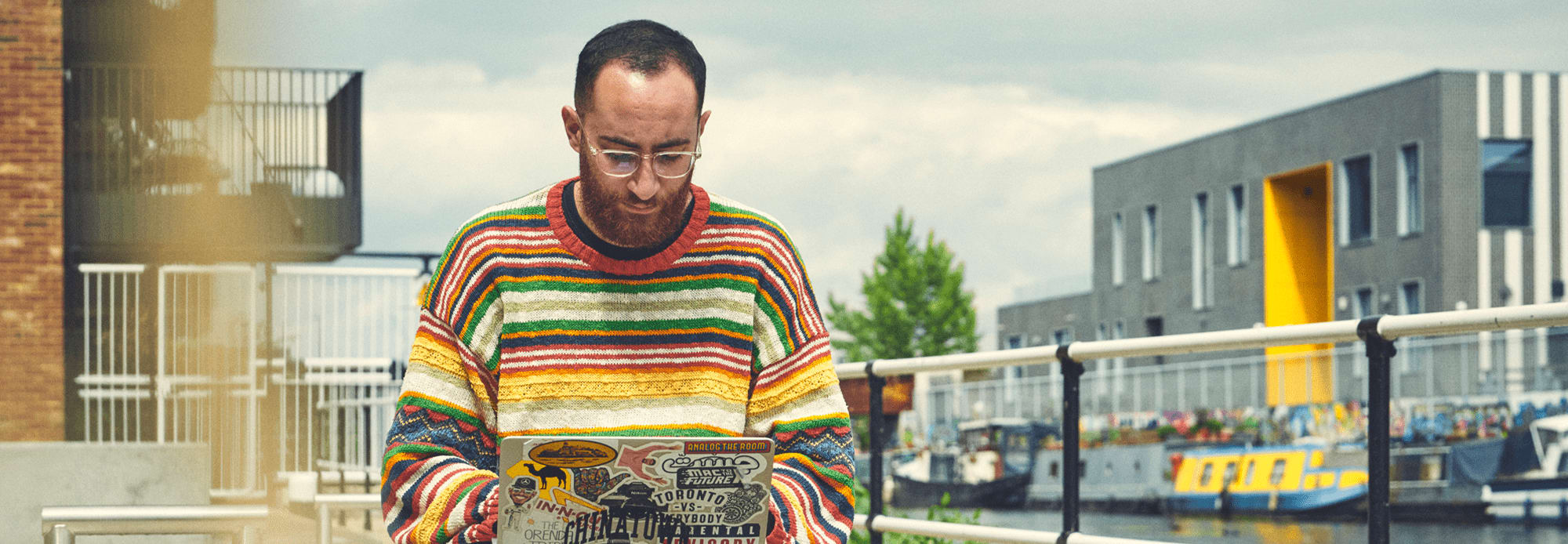 Student working on a laptop outside sitting by a canal