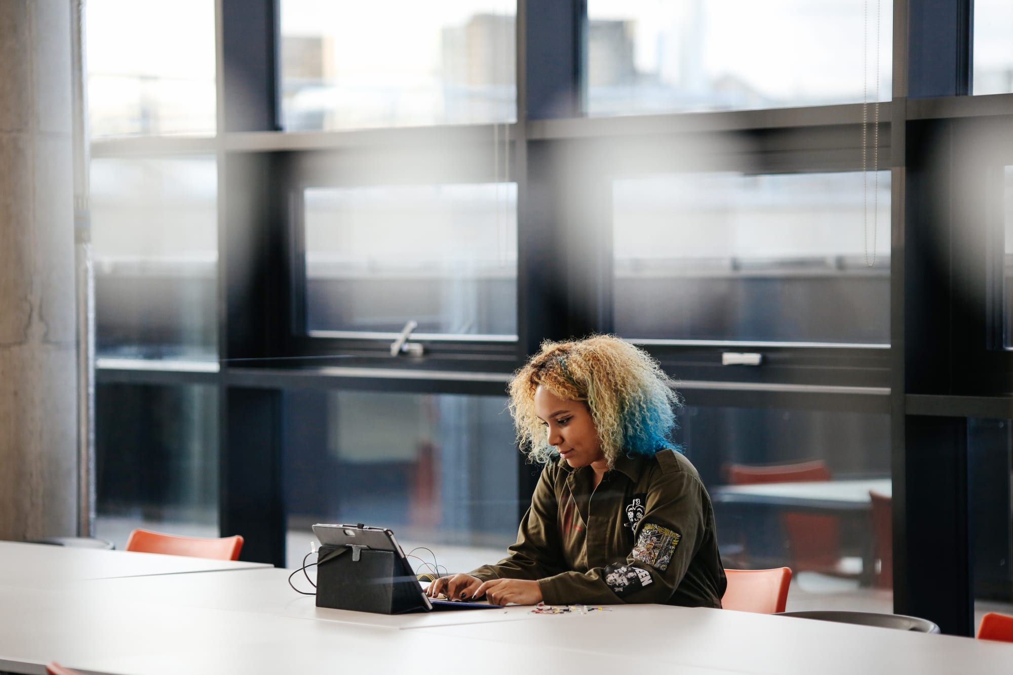 Woman sitting on laptop with electronics components