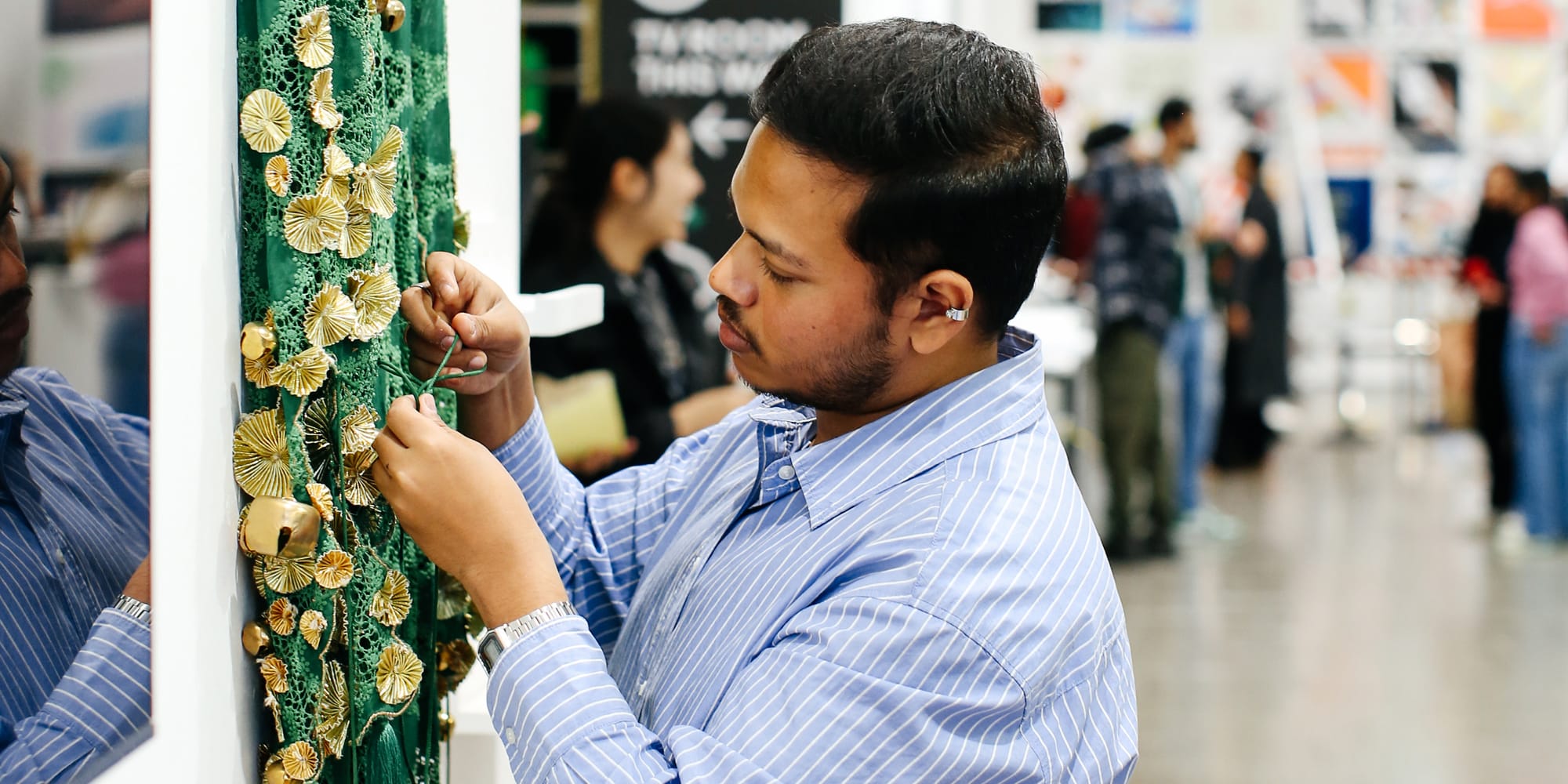 student working on embroidery at an exhibition