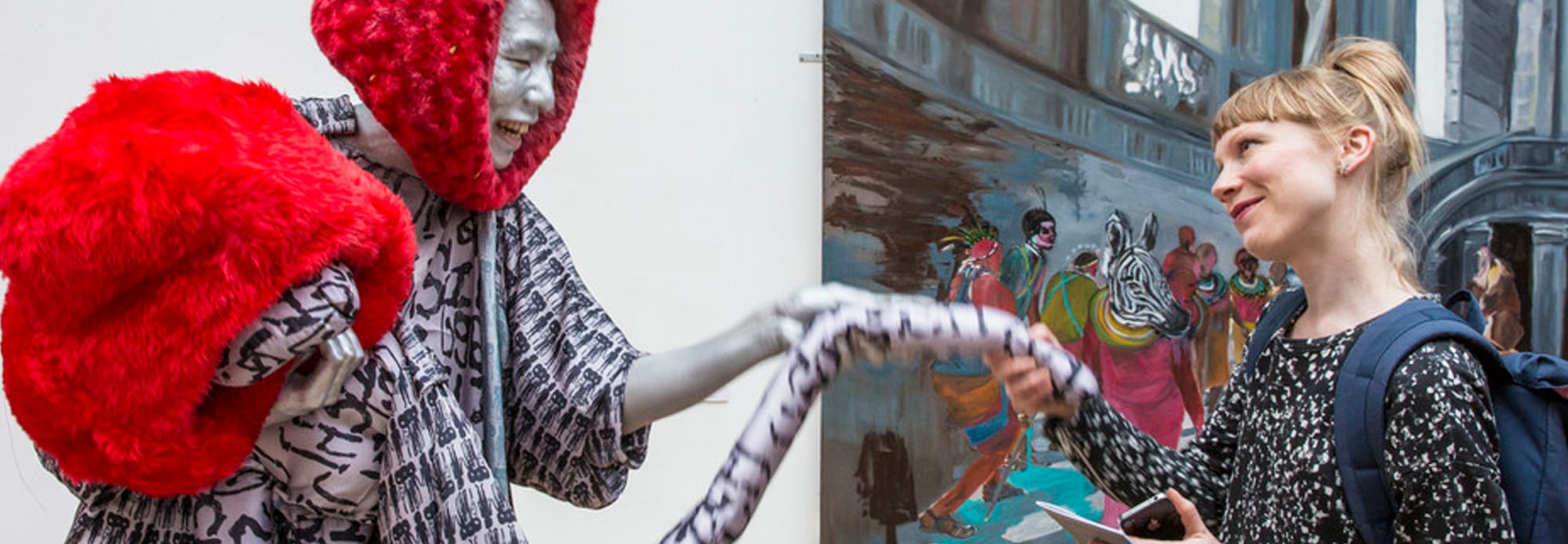 An performer in silver make-up interacting with a young woman 