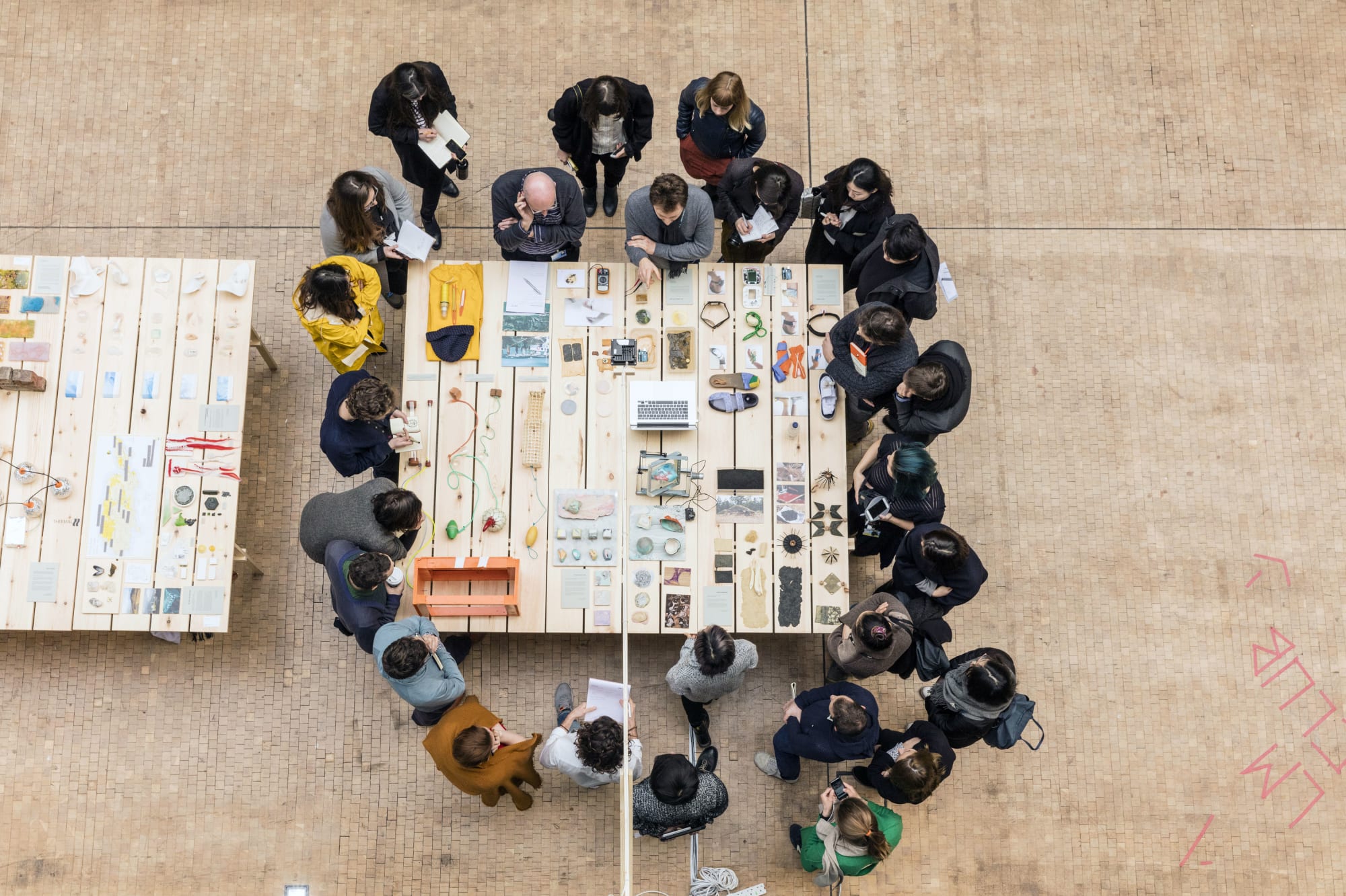 Group of people gathered around a table looking at different objects and devices
