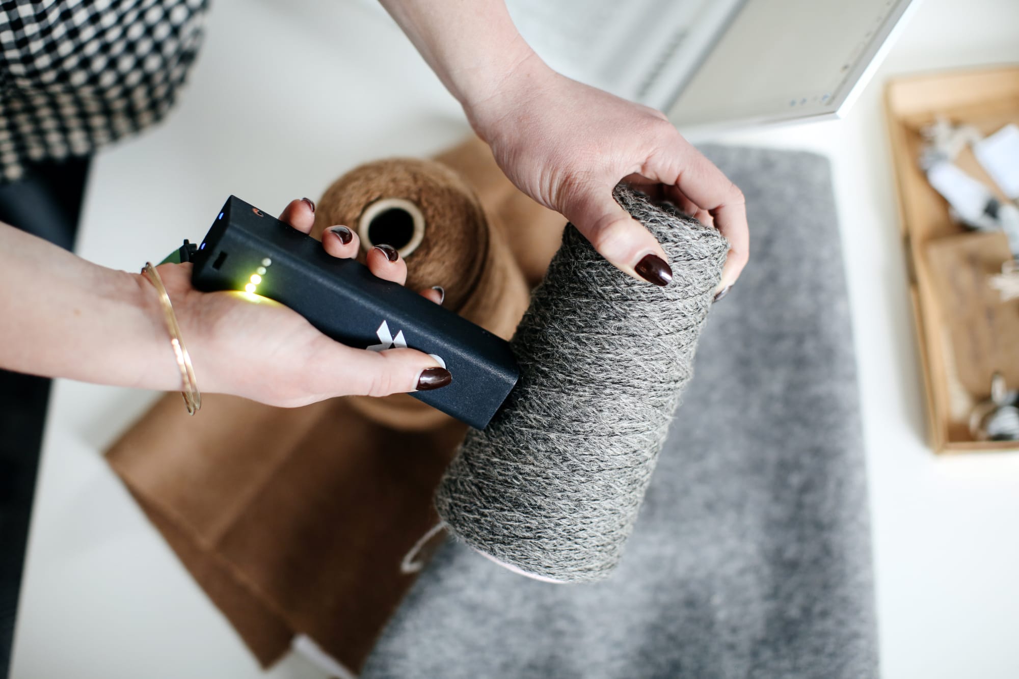 A photo of someone scanning a reel of yarn to trace what fibre it is made from. 