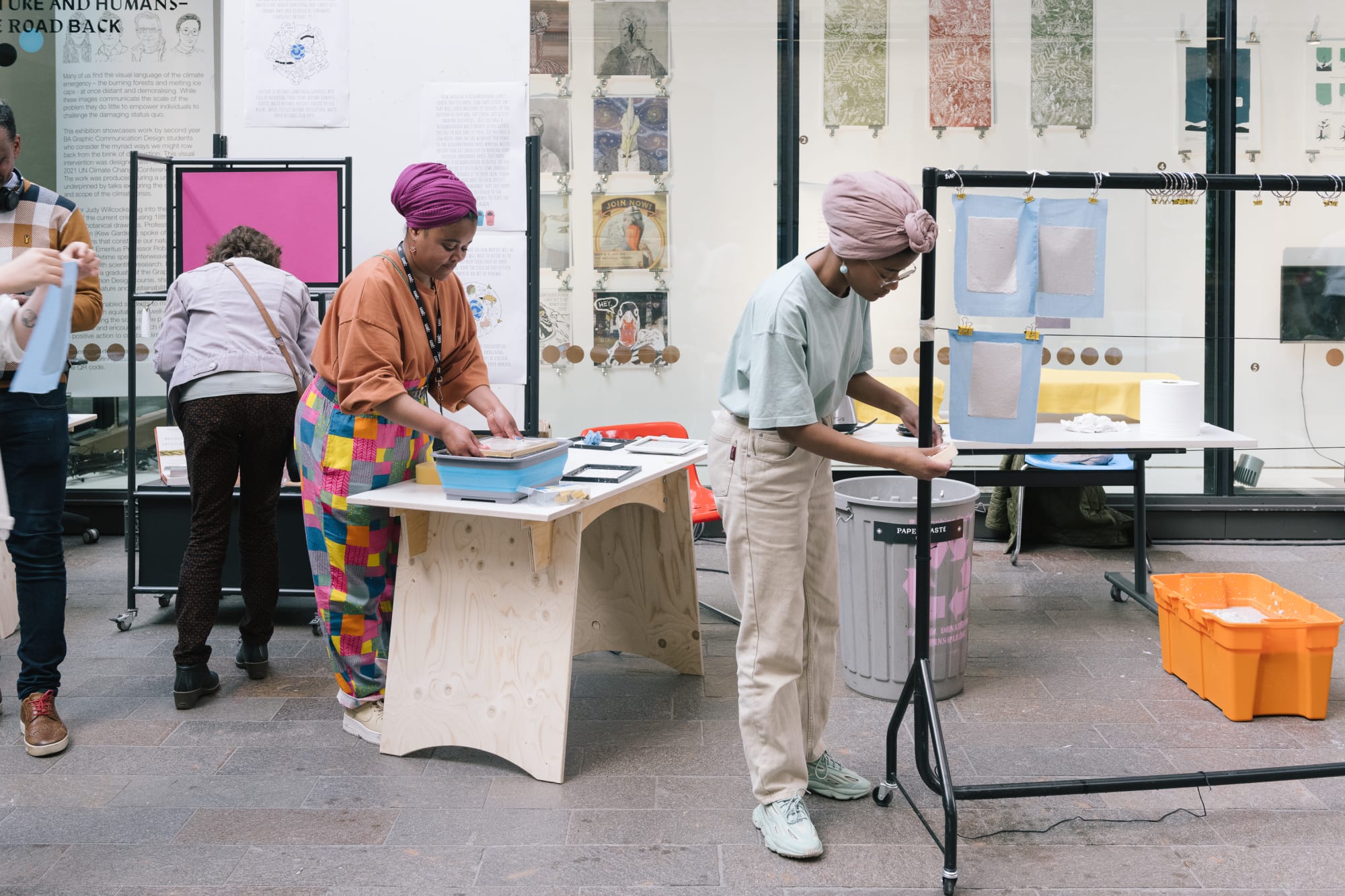 People making and working in the wide open space of the Crossing on CSM's campus. Rails, tables, boxes and artworks are pinned up all around.