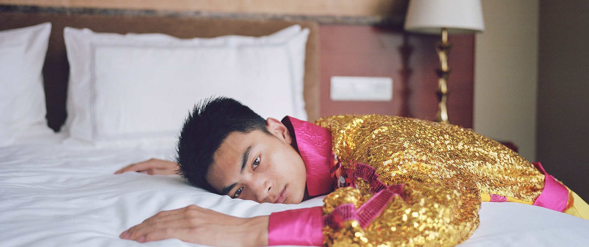 A person lying on a bed and looking straight to camera.