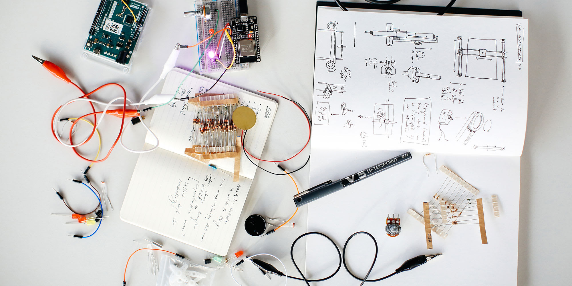 Close up image of lots of computational equipment and a work book with lots of notes