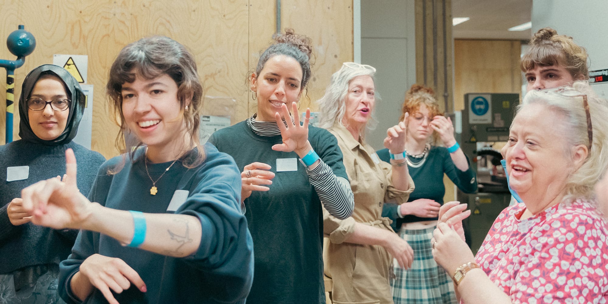 A group of teachers standing together in the jewellery workshop showing off the rings they've made on their fingers