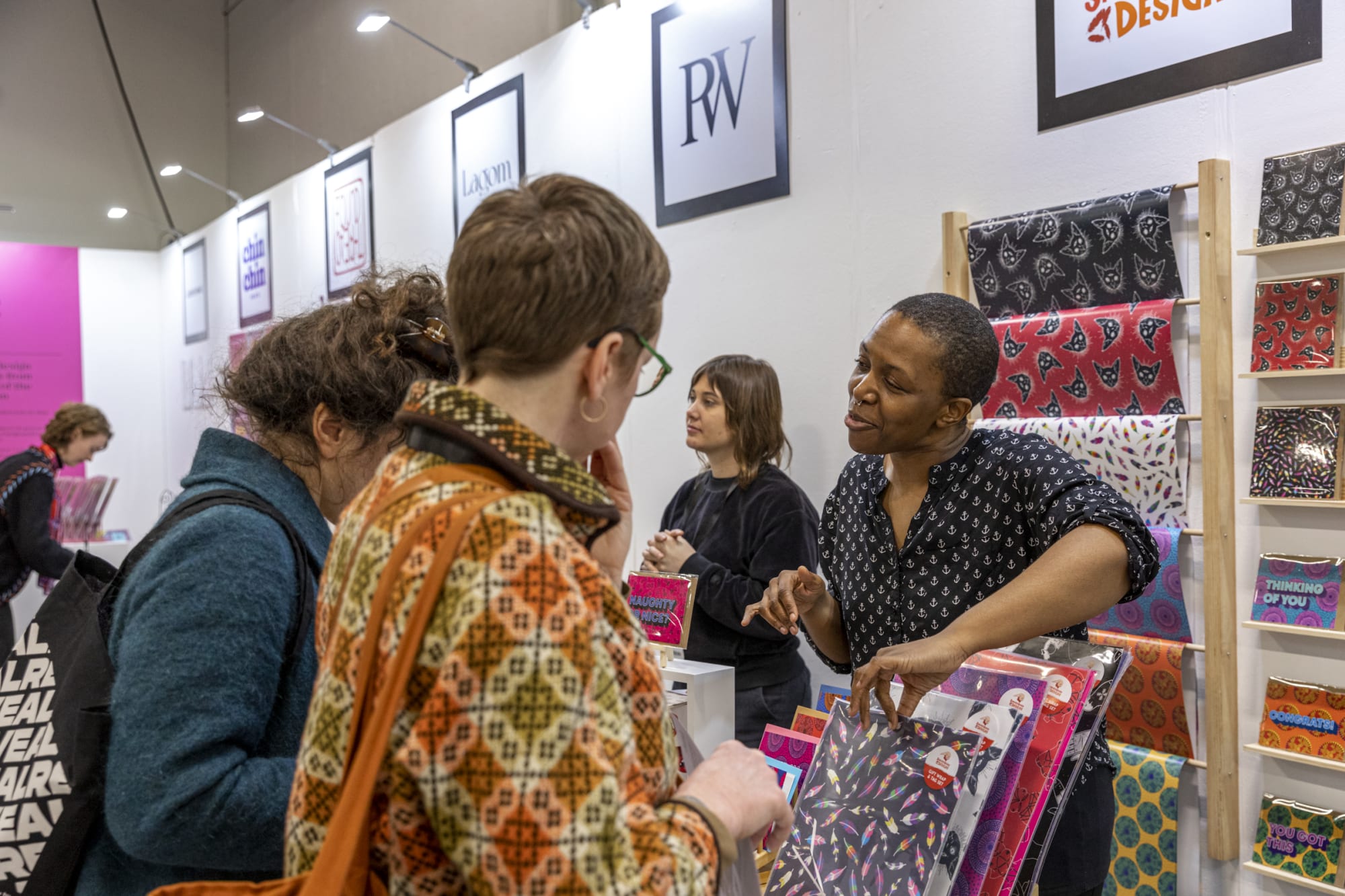  People at a booth in a trade show discussing colorful patterned products displayed on shelves