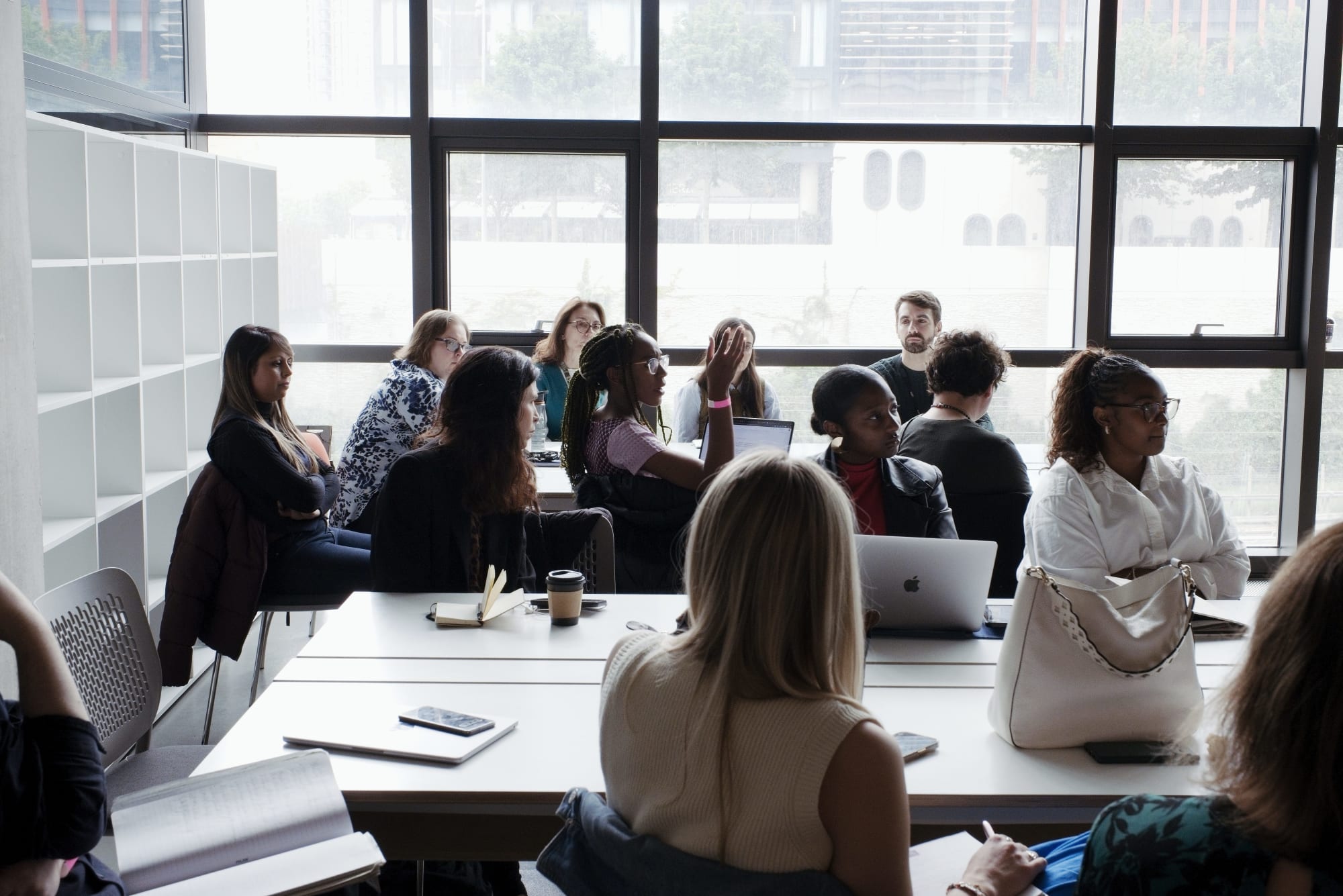 People at a table in front of a window, engaging in discussion