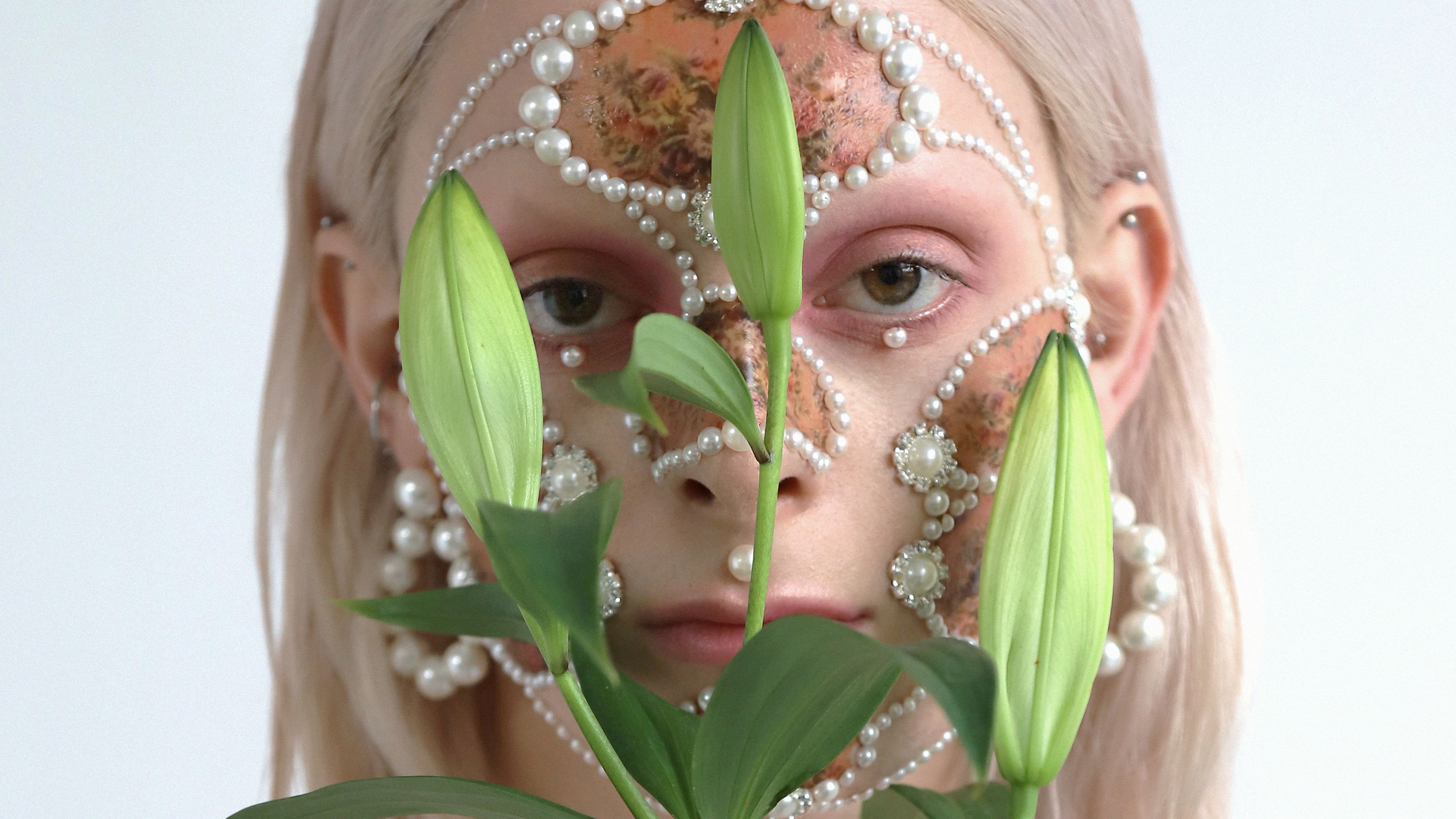 Female model with pearl facial jewellery, makeup and lilies.
