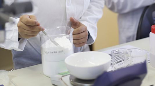Scientists in labs wearing white robes and using different tools to create cosmetic products