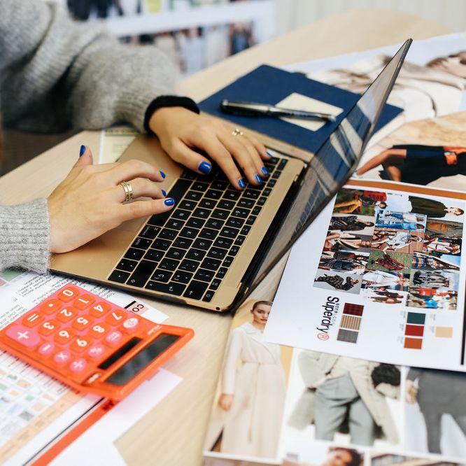 Woman on a laptop with a calculator beside her, MA Fashion: Buying and Merchandising (now PG Cert Fashion: Buying and Merchandising), Zoe Zanon Rives in the studio