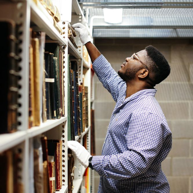 Black man researching in archives wearing white gloves