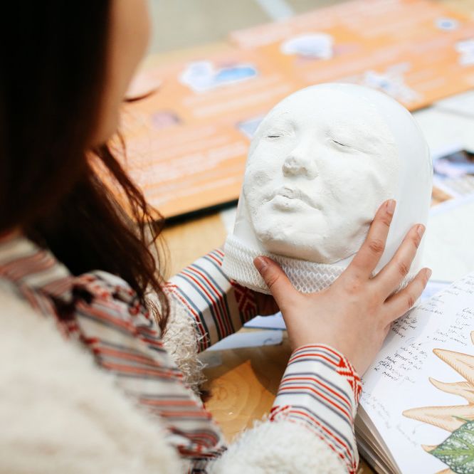 Student holding a cast of someone's face.