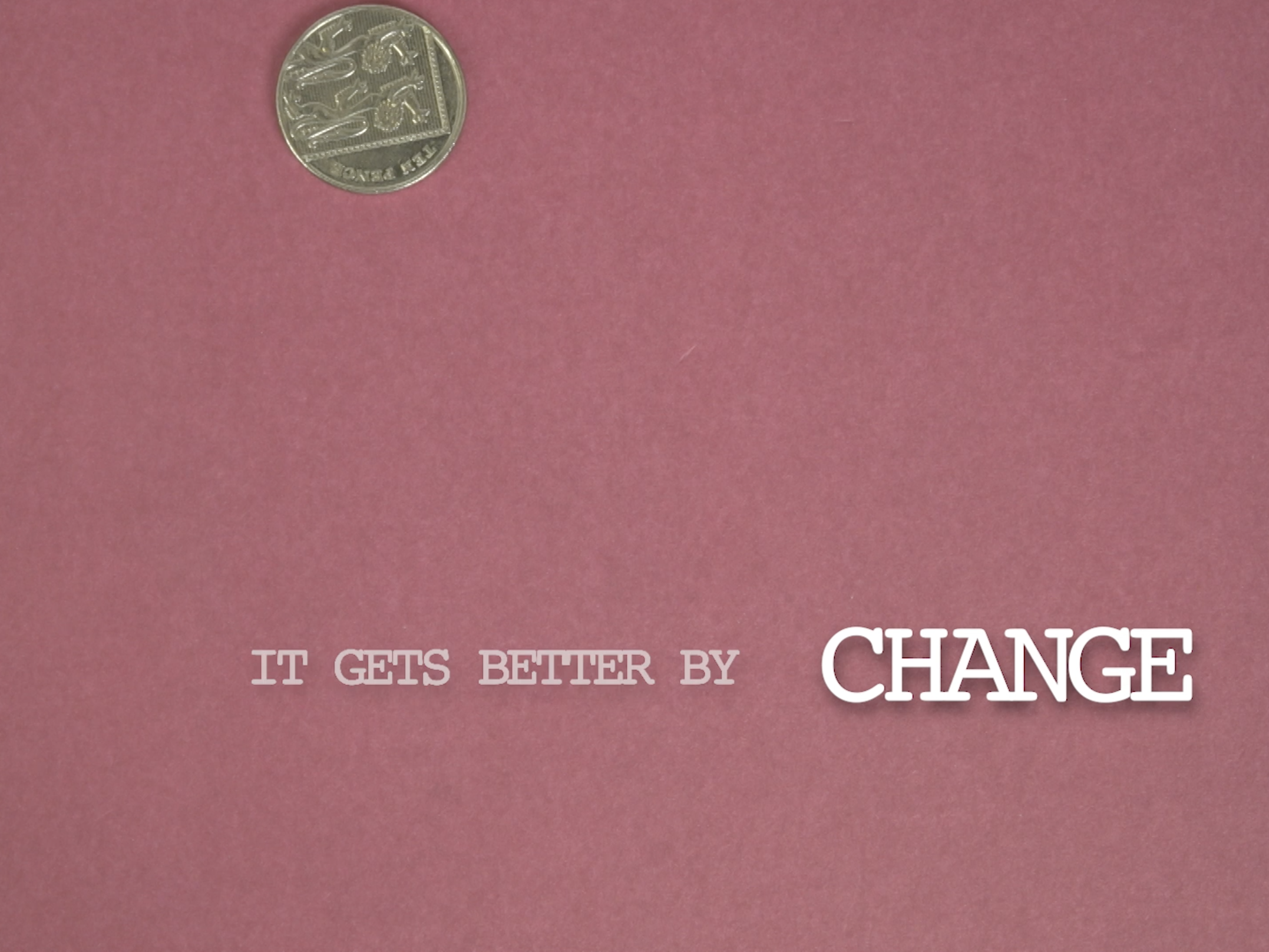A still of a coin falling in front of a pink background.