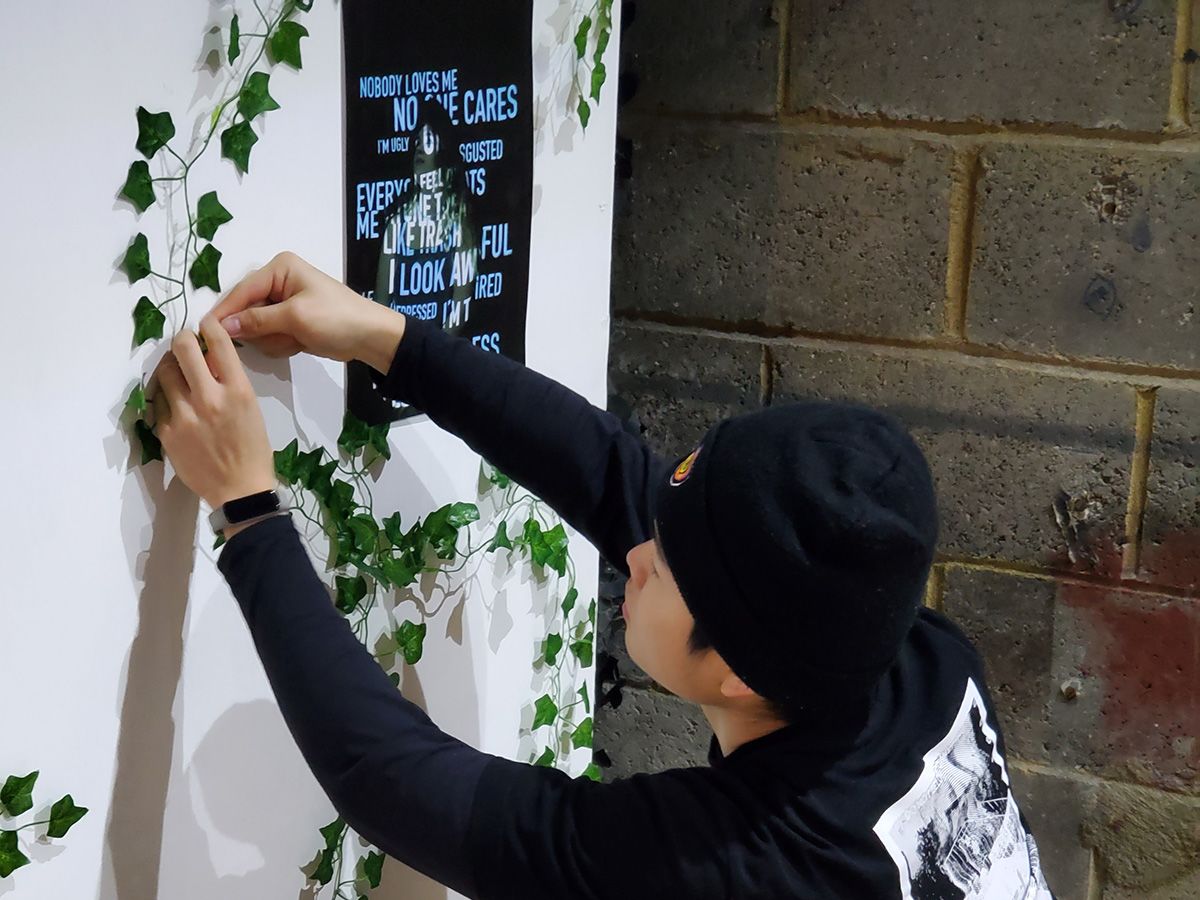 A man crouches down to assemble an exhibition wall.